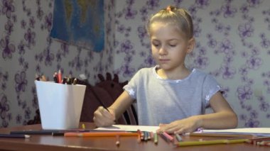 Bir kağıt üzerine renkli kalemler ile boyar küçük güzel kız. Çocuk yaratıcılık