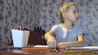 Bir kağıt üzerine renkli kalemler ile boyar küçük güzel kız. Çocuk yaratıcılık