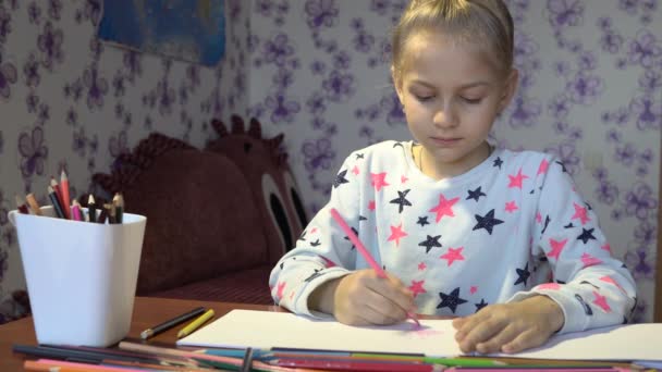 Яскрава мила дівчинка малює з олівцями на білих аркушах — стокове відео