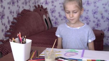 Sevimli küçük bir kız albümde renkli kalemler ve boyalar ile çizer. Çocuk yaratıcılık