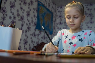 Çocuk resim renkli kalemler ile çizer.