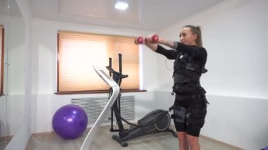 Güzel atletik esmer dumbbells ile EMS egzersizleri yapıyor. El alıştırmaları