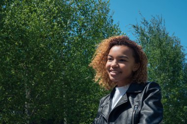 Şirin Afrikalı kız düşünceli uzakta bahar dışında güzel bir gülümseme ile görünüyor