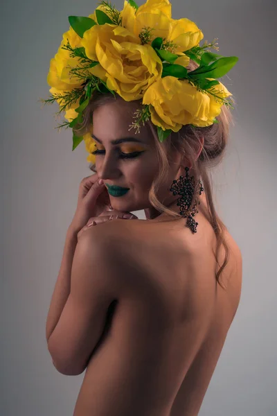 Fashion portrait from the back of a sexy girl with bright makeup and a wreath of bright colors