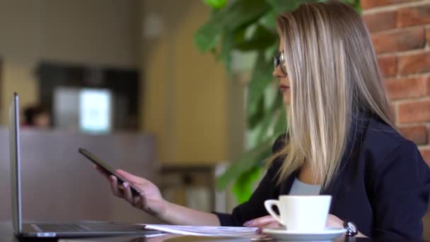 Joven mujer de negocios mirando gráficos y hablando por teléfono . — Vídeos de Stock