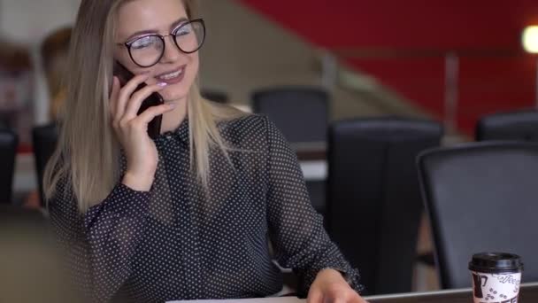 Joven mujer de negocios exitosa en un café hablando por teléfono — Vídeos de Stock