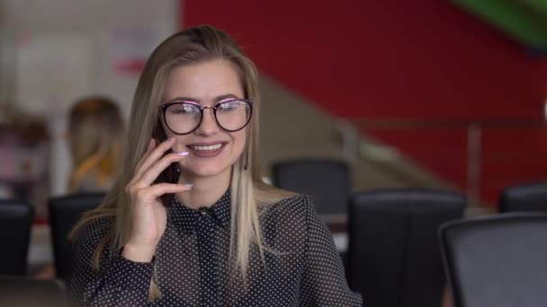 Ung affärskvinna i ett café som pratar i telefon — Stockvideo