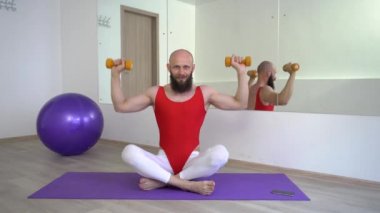 Kırmızı bodysuit ve beyaz tozluk komik kel adam elinde halter ile Lotus pozisyonda oturan etrafında aptal