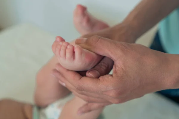 Bir kadına yakın çekim bir çocuğun bacağını tutan el. Bebek masajı. — Stok fotoğraf