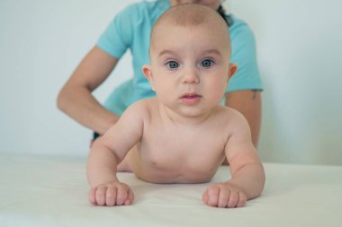 Büyük güzel gözleri olan sevimli küçük bir bebeğin portresi. Küçük bir çocuğa masaj yapan bir kadın. Bebek masajı