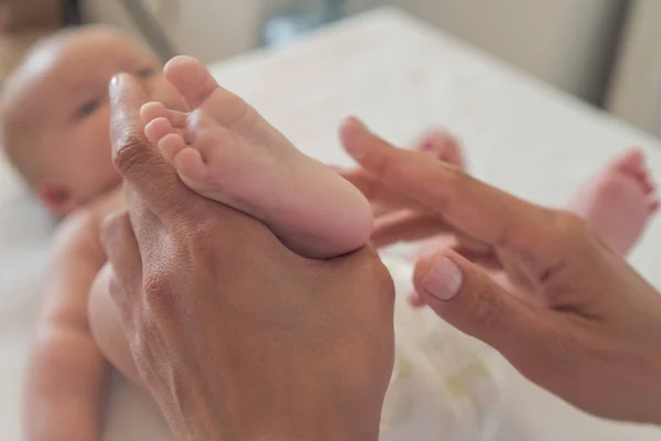 Massagem nos pés. Close-up Uma mulher massageia o pé de um bebê recém-nascido . — Fotografia de Stock