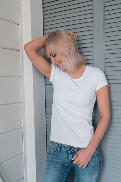 Портрет милой блондинки в белой футболке отворачивается от камеры и смеется — стоковое фото