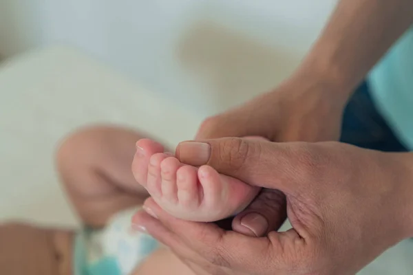 Los pies pequeños del bebé en las manos de las mujeres. El concepto de maternidad, cuidado y calidez —  Fotos de Stock