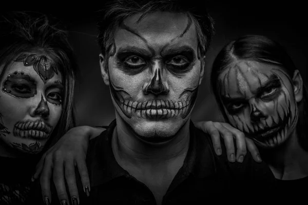 Manliga och kvinnliga ansikte konst för Halloween. Svart och vitt porträtt av en kille och två flickor med skrämmande målade ansikten på en svart bakgrund. All Saints Night. — Stockfoto