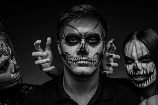 Manliga och kvinnliga ansikte konst för Halloween. Svart och vitt porträtt av en kille och två flickor med skrämmande målade ansikten på en svart bakgrund. All Saints Night. — Stockfoto