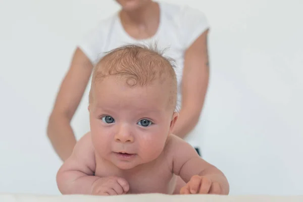 Komik bir bebek doğrudan kameraya bakıyor ve bir kadın arka planda bir bebeği tutuyor.. — Stok fotoğraf