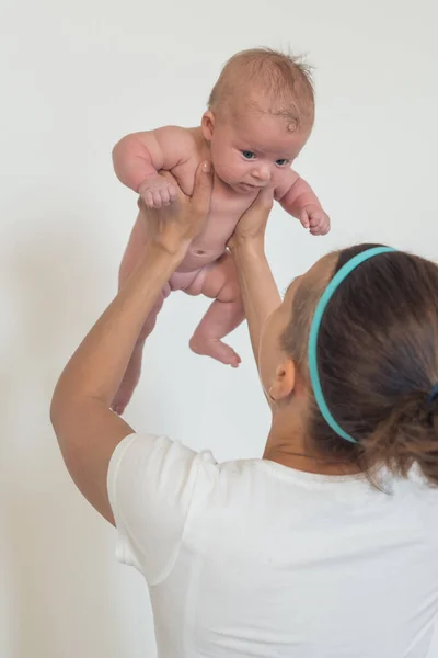 Retrato de una mujer sosteniendo a un bebé desnudo en sus brazos, elevado por encima de su cabeza. El concepto de maternidad. Madre e hijo —  Fotos de Stock
