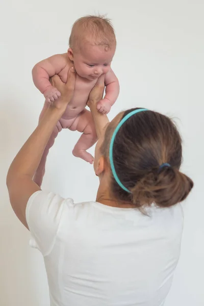 Portrait d'une femme tenant un bébé nu dans ses bras, élevé au-dessus de sa tête. Le concept de maternité. Mère et enfant — Photo