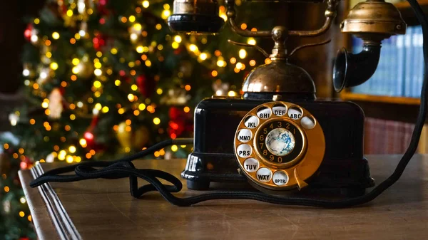 Retro phone close up and Christmas tree in the background — Stock Photo, Image