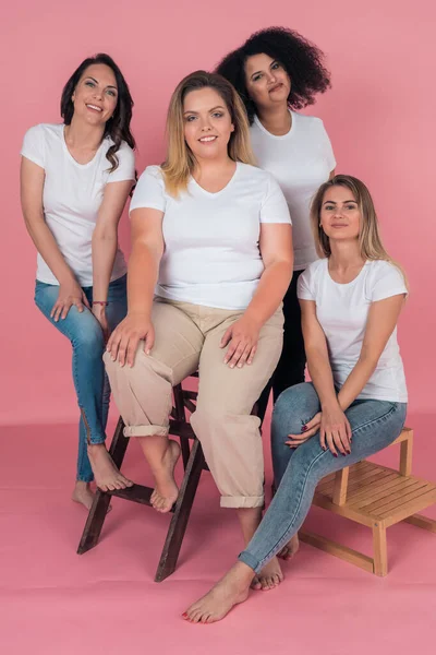 Een groep mooie glimlachende meisjes poseren vol gezicht voor de camera op een roze achtergrond — Stockfoto