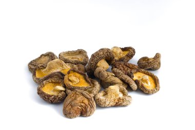 Beyaz bir zemin üzerinde kurumuş shiitake mantarlarının sanatsal yakın çekimi karmaşık dokularını ve derin doğal renklerini sergiliyor. Gurme için mükemmel, organik besin tasvirleri..