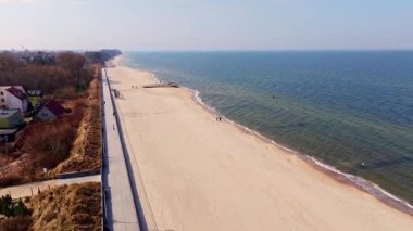 İnsansız hava aracı, Sarbinowos 'un geniş kumlu sahillerinde uçuyor ve Baltık Denizi' ni sakin tutuyor. Köyün gezinti güvertesini ve bahar güneşini gözler önüne seriyor..