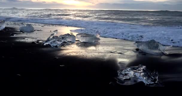 波は岸に実行し 氷の部分に激しく打ちつけた アイスランドの海の日の出の海岸 — ストック動画