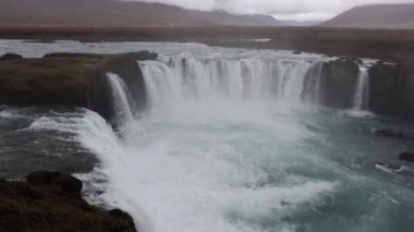 Güçlü azgın whitewater şelale zorla kayalık bir kenarın üzerine düşüyor. Kristal berraklığında buzul su akışı uçurumdan düşüyor