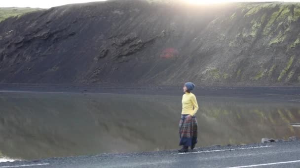 若い女性は 美しい山間の湖の背景に山の中の道を歩きます 彼女はハッピー ハッピー 賞賛と喜びと楽しみを持つ — ストック動画