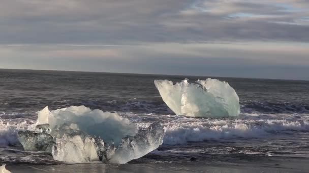 冰山和一片蓝色和白色的冰卷在波浪上 海浪在冰上破碎 日出时在海滩上冲浪 慢动作 — 图库视频影像