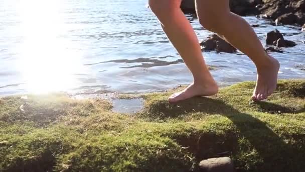 Дівчина Біжить Босоніж Зеленому Пляжі Моху Сонячні Промені Відбиваються Воді — стокове відео