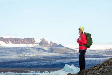 Sırt çantası ile sportif kız buz göl ve dağların güzel manzarasına hayran. İzlanda'daki buz lagoon