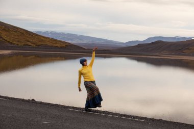 Kız sarı nehir ve yükselen güneş ışınlarının Hill'de manzarasına hayran. İzlanda'daki sabah erken gün. İzlanda'da araba Turizm.
