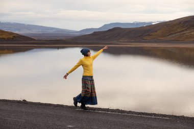 Kız sarı nehir ve yükselen güneş ışınlarının Hill'de manzarasına hayran. İzlanda'daki sabah erken gün. İzlanda'da araba Turizm.