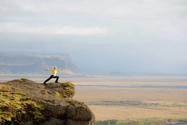 View of a young slim tourist girl standing on rocky peaks on a bright blue morning morning and foggy mountains background. Tourism, travel and climbing.