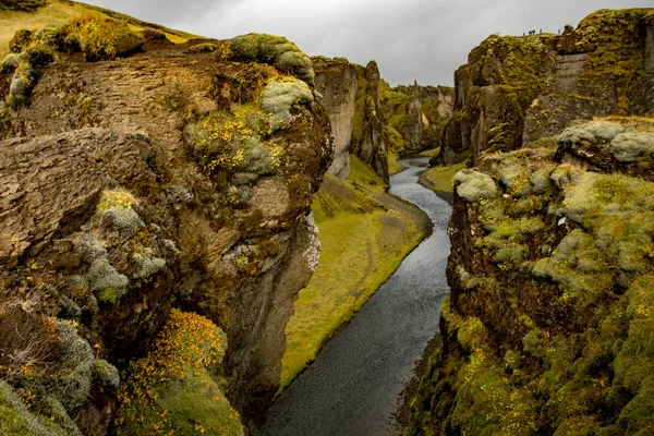 Deep canyon, steep cliffs overgrown with green moss, surrounded by a very fast river with cold water. Canyon of Icelandic tales - Fjardrarglufur