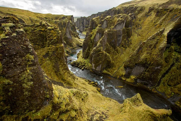 Deep canyon, steep cliffs overgrown with green moss, surrounded by a very fast river with cold water. Canyon of Icelandic tales - Fjardrarglufur