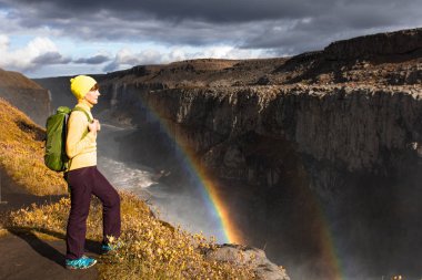 Avrupa - Dettifoss'ın en güçlü şelale düşen su kıyısında genç bir kadın duruyor. Renkli yaz günü Jokulsarglufur Milli Parkı, İzlanda