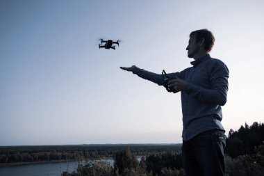 Bir adam quadcopter başlattı. Dron nehir ve orman üzerinde uçan güneşli bir günde