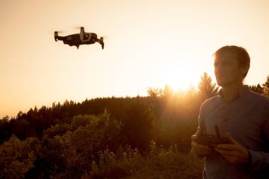 Bir adam quadcopter başlattı. Dron nehir ve orman üzerinde uçan güneşli bir günde