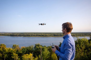 Bir adam quadcopter başlattı. Dron nehir ve orman üzerinde uçan güneşli bir günde