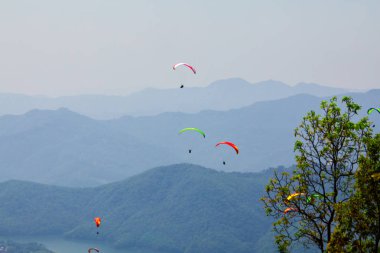 Uçan bir Yamaçparaşütü üzerinde. Güzel manzara dağlar ve renkli paraşütler ile. Aşırı tatil seyahat