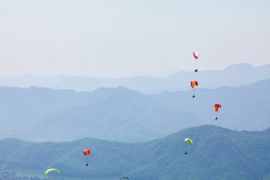 Uçan bir Yamaçparaşütü üzerinde. Güzel manzara dağlar ve renkli paraşütler ile. Aşırı tatil seyahat