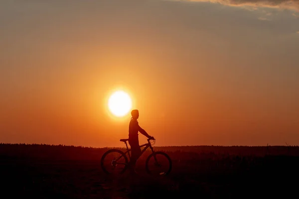 Dziewczyna Jeździ Rowerem Drodze Tle Jasnego Zachodu Słońca Żółtego Słońca — Zdjęcie stockowe