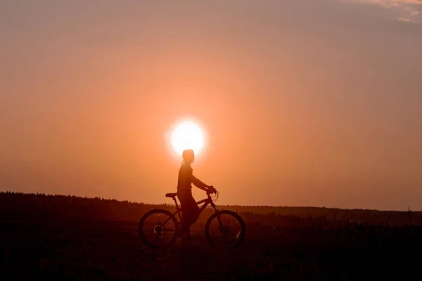 Dziewczyna Jeździ Rowerem Drodze Tle Jasnego Zachodu Słońca Żółtego Słońca — Zdjęcie stockowe