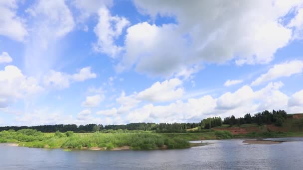 Des nuages traversent le ciel bleu. Temps écoulé. En aval de la rivière coule et la forêt grandit 