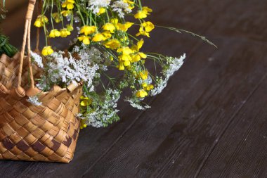 Çiçekli hasır sepet ahşap bir masanın üzerinde duruyor