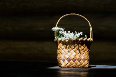 Çiçekli hasır sepet ahşap bir masanın üzerinde duruyor