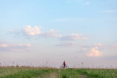 Mavi gökyüzü ve yeşil çim bir arka plan üzerinde bisiklet kız