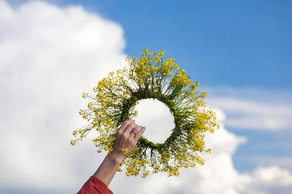 A wreath of flowers in the girls hand in the sky